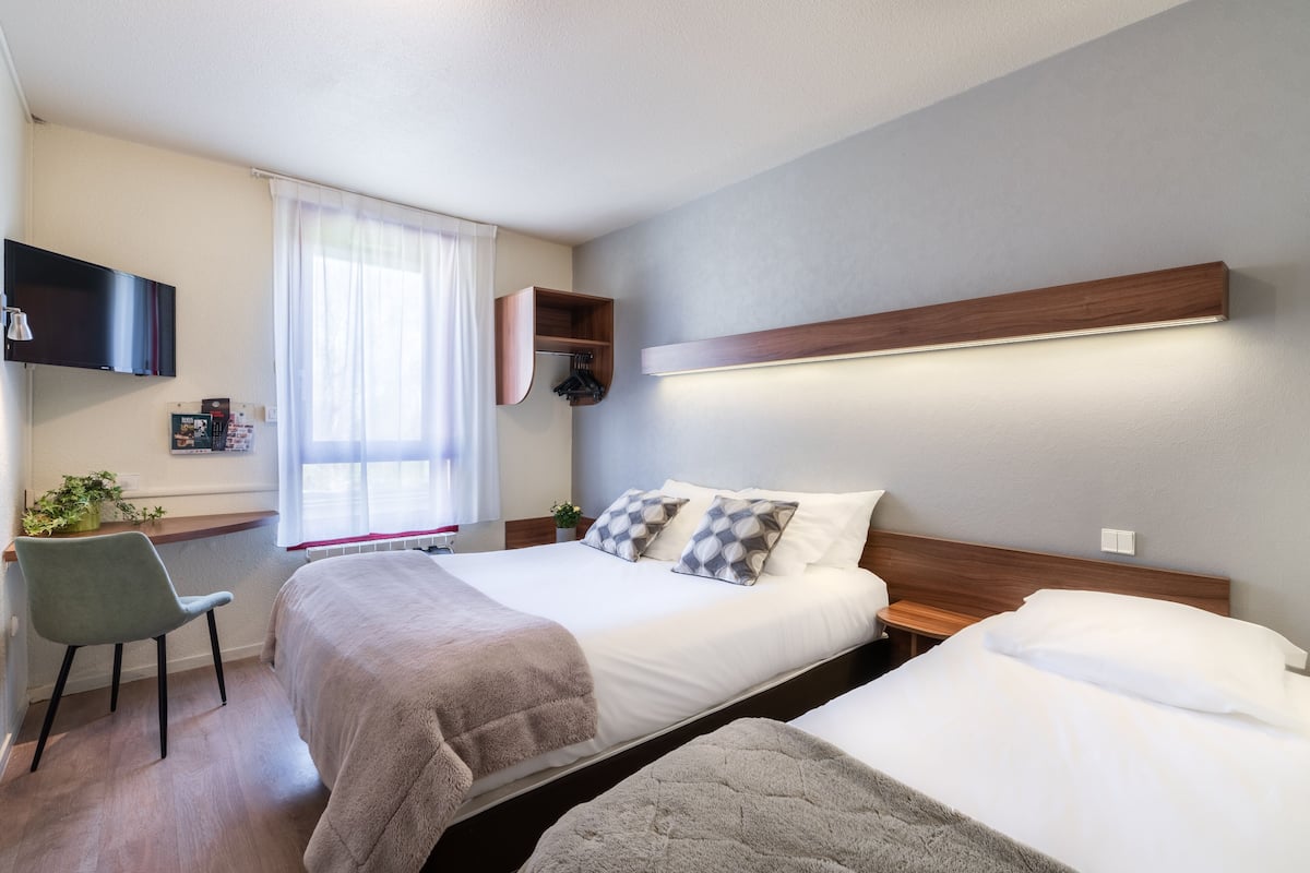 Une chambre d’hôtel moderne, dotée d’un grand lit, de tables de chevet, d’un bureau et d’une chaise.
