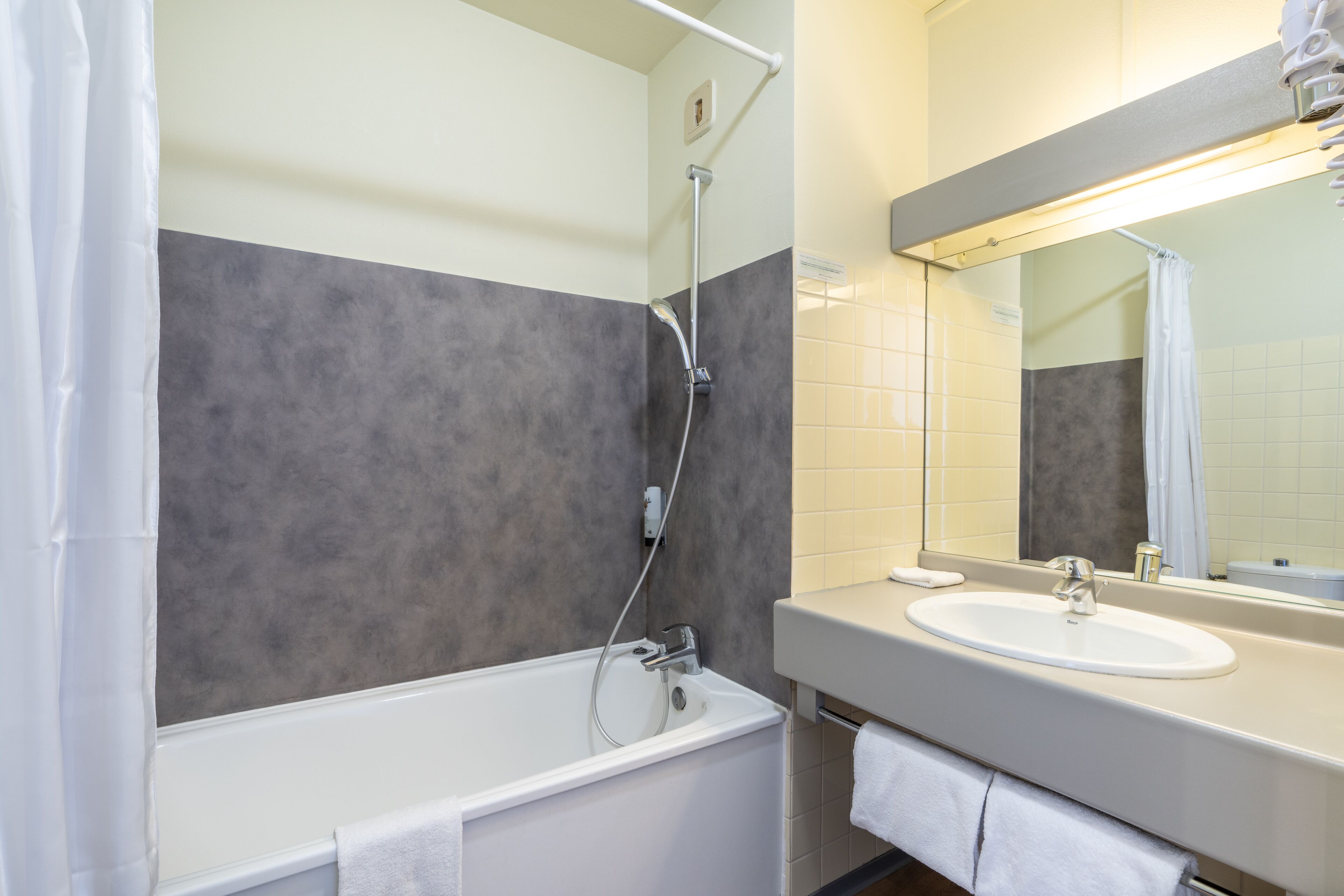 Une salle de bain moderne avec une baignoire, un lavabo et un miroir.