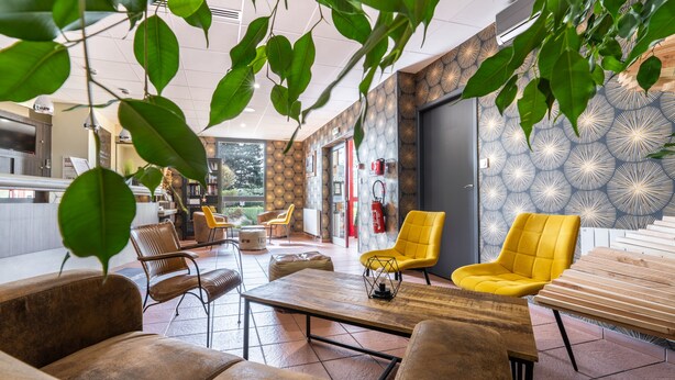 Un espace intérieur moderne doté de coins salon, d’un extincteur et d’un mur orné de motifs.