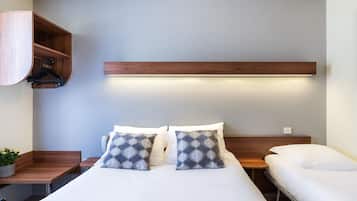 A hotel room with a bed, bedside tables, a wooden shelf, and a hanging light fixture.