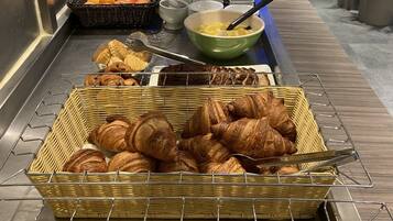 Un bufé con diversas opciones de panadería, incluyendo croissants, pan y pastelería.