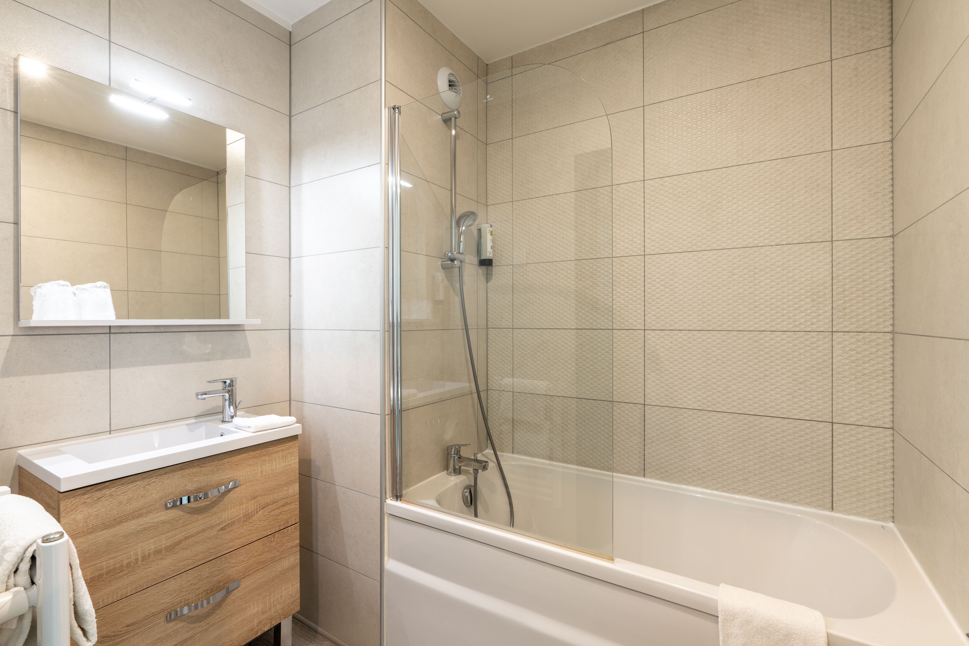A modern bathroom with a glass-enclosed shower, a wooden vanity with a sink, and a large mirror.