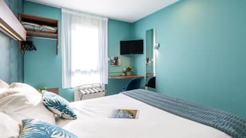 Une chambre à coucher avec un lit, un bureau, une chaise, un téléviseur et une fenêtre avec des rideaux.