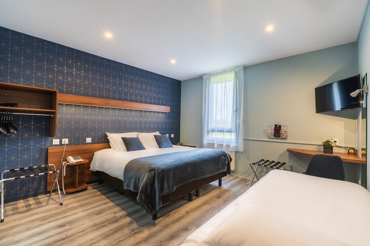 Une chambre d’hôtel moderne, dotée d’un grand lit, d’un bureau et d’une télévision.