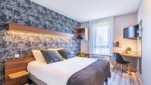 Une chambre d’hôtel moderne, dotée d’un grand lit, d’un bureau avec une chaise, d’une télévision et d’une fenêtre avec des rideaux.