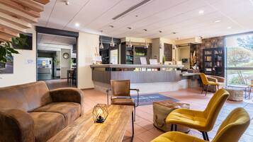 A modern lobby with a reception desk, seating area, and a bookshelf.