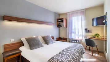 Una habitación de hotel moderna con una cama grande, un escritorio, una silla y una televisión.