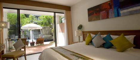 A hotel room with a large bed, a view of a pool and outdoor area, and a painting on the wall.