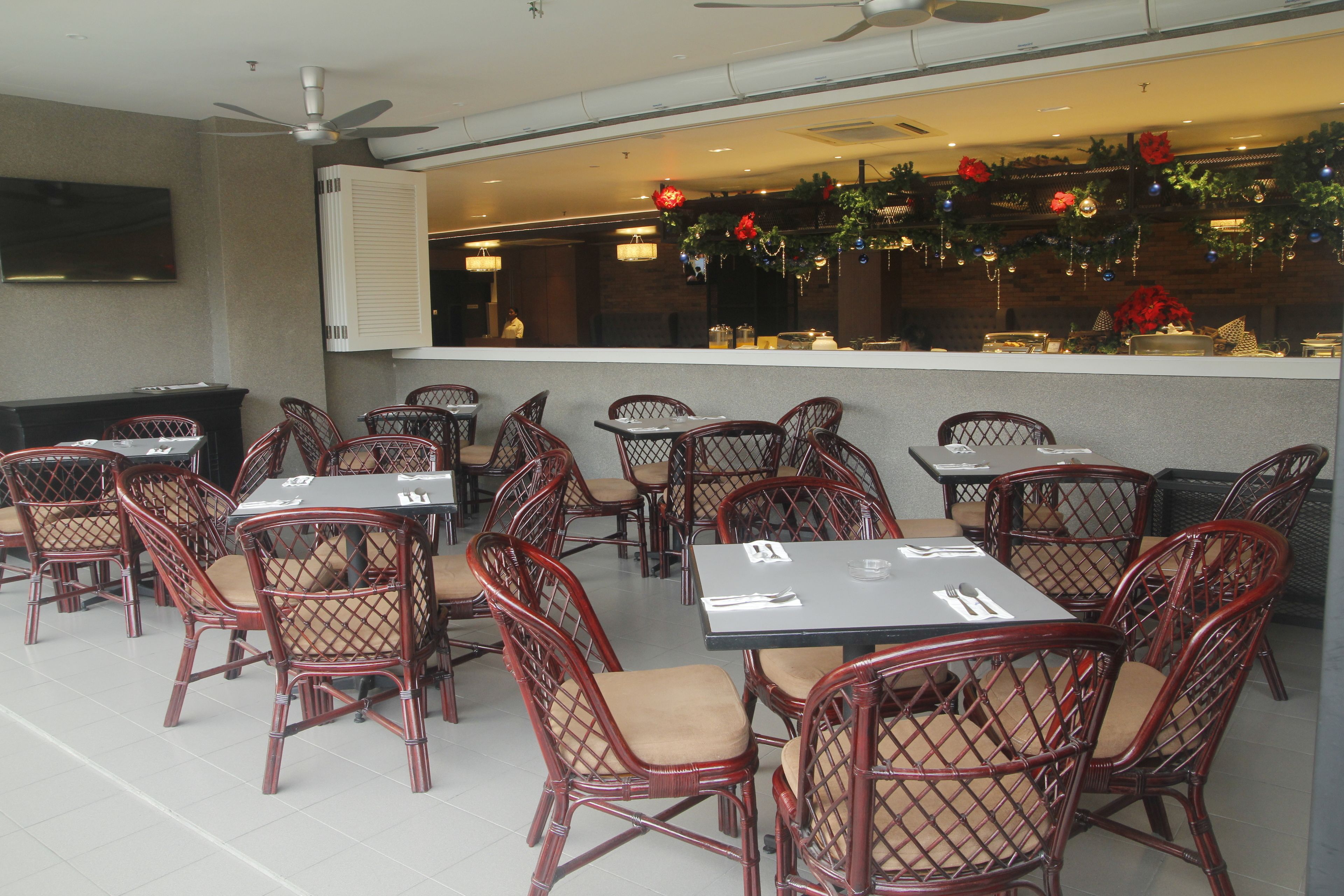 Un restaurante con sillas y mesas de mimbre, un ventilador de techo y una decoración alegre.