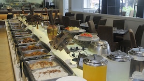 Buffet amb diverses opcions de menjar, incloent arròs, carns i verdures, i una zona de begudes amb gerros.