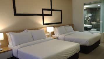 Ein Hotelzimmer mit zwei Betten, einem großen Spiegel und einem durch eine Glastrennwand einsehbaren Badezimmer.