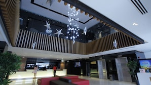 Un vestíbul modern amb taulell d'informació, zona de seients i llums decoratives amb forma d'estrelles.