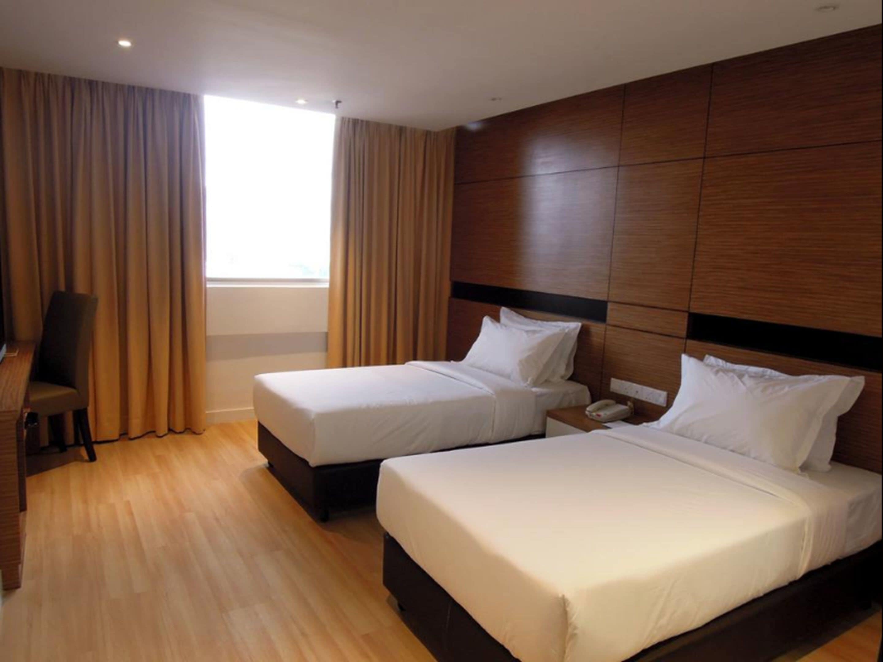 A hotel room with two beds, a desk, and a chair.