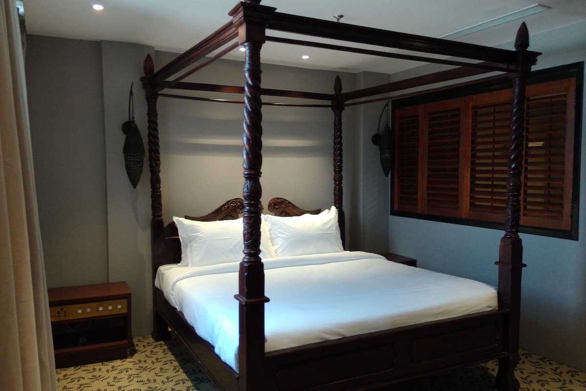 A four-poster bed with a wooden frame and white linens.