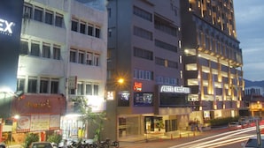 Un hotel de diverses plantes amb un disseny modern, amb un rètol destacat a la part superior i diverses botigues a nivell de carrer.