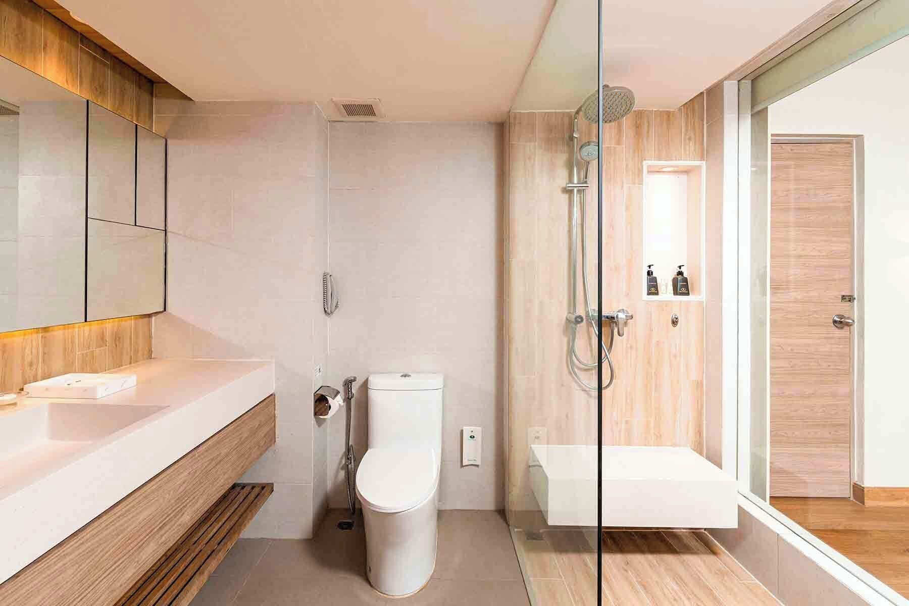 A modern bathroom with a glass shower enclosure, a wooden vanity, and a white toilet.