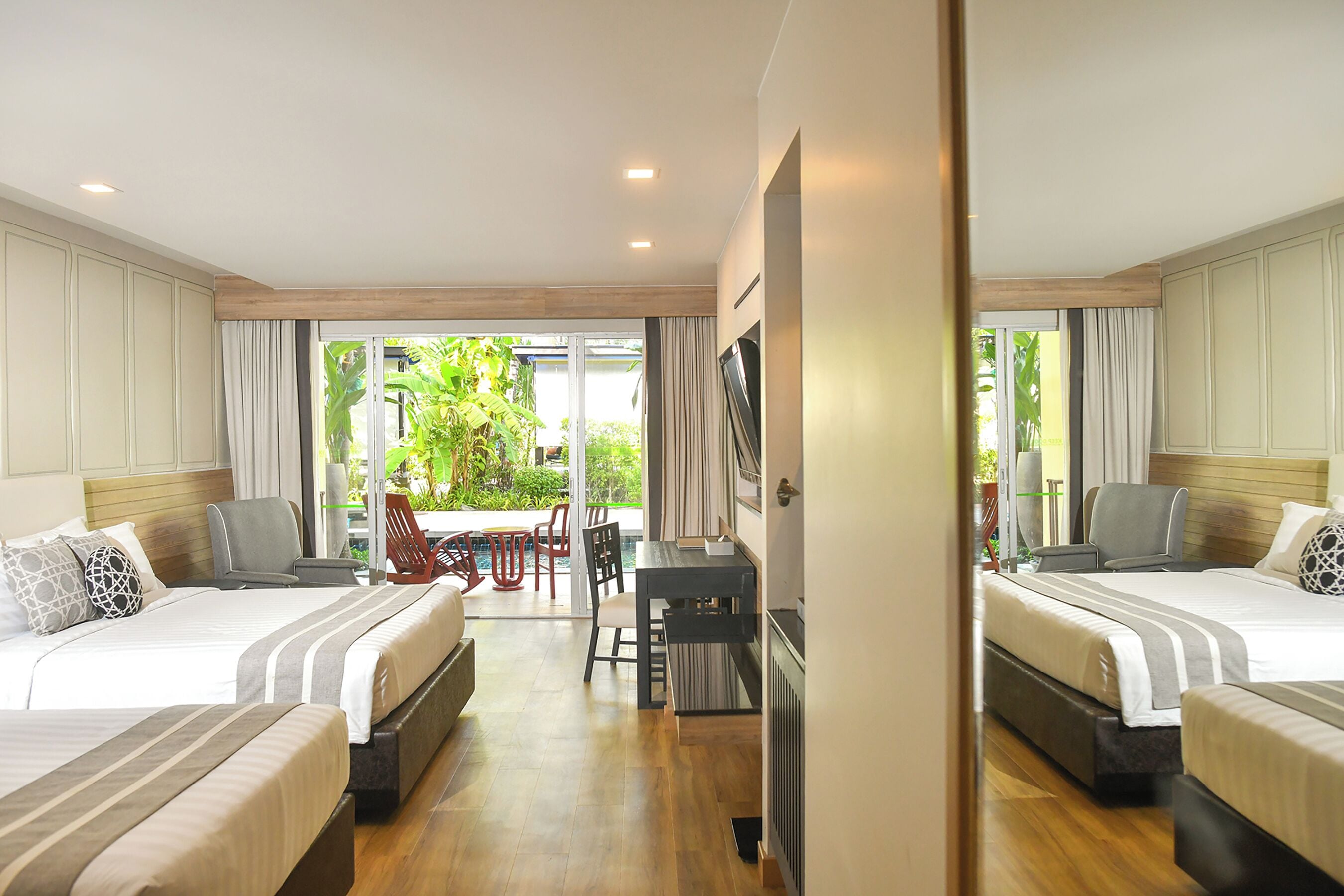 A hotel room with two beds, a desk, and a view of the outdoors.