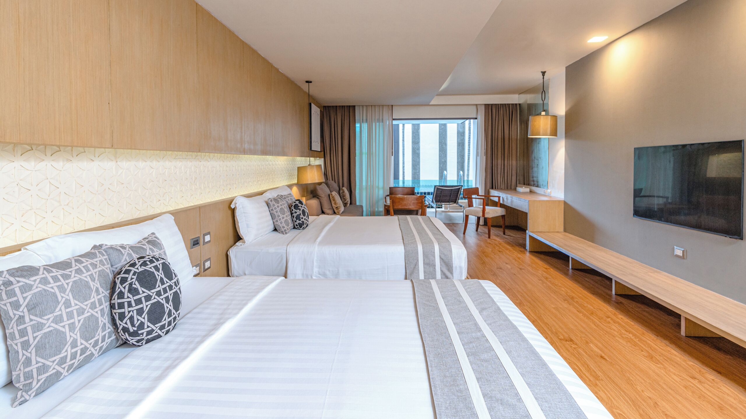 Una camera d'hotel con due letti, una scrivania, una sedia, una TV e vista sulla città.