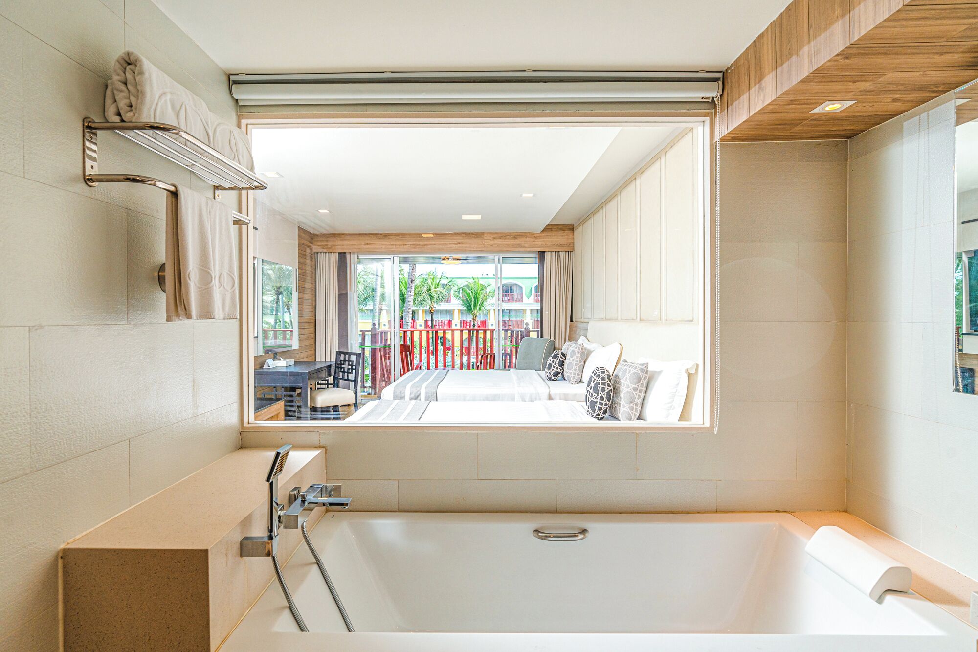 Un baño moderno con una bañera grande, zona de ducha y vistas a un balcón con mobiliario exterior.