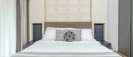 A neatly made bed with a striped bedspread, a headboard with a woven pattern, and two bedside tables with dark-colored nightstands.