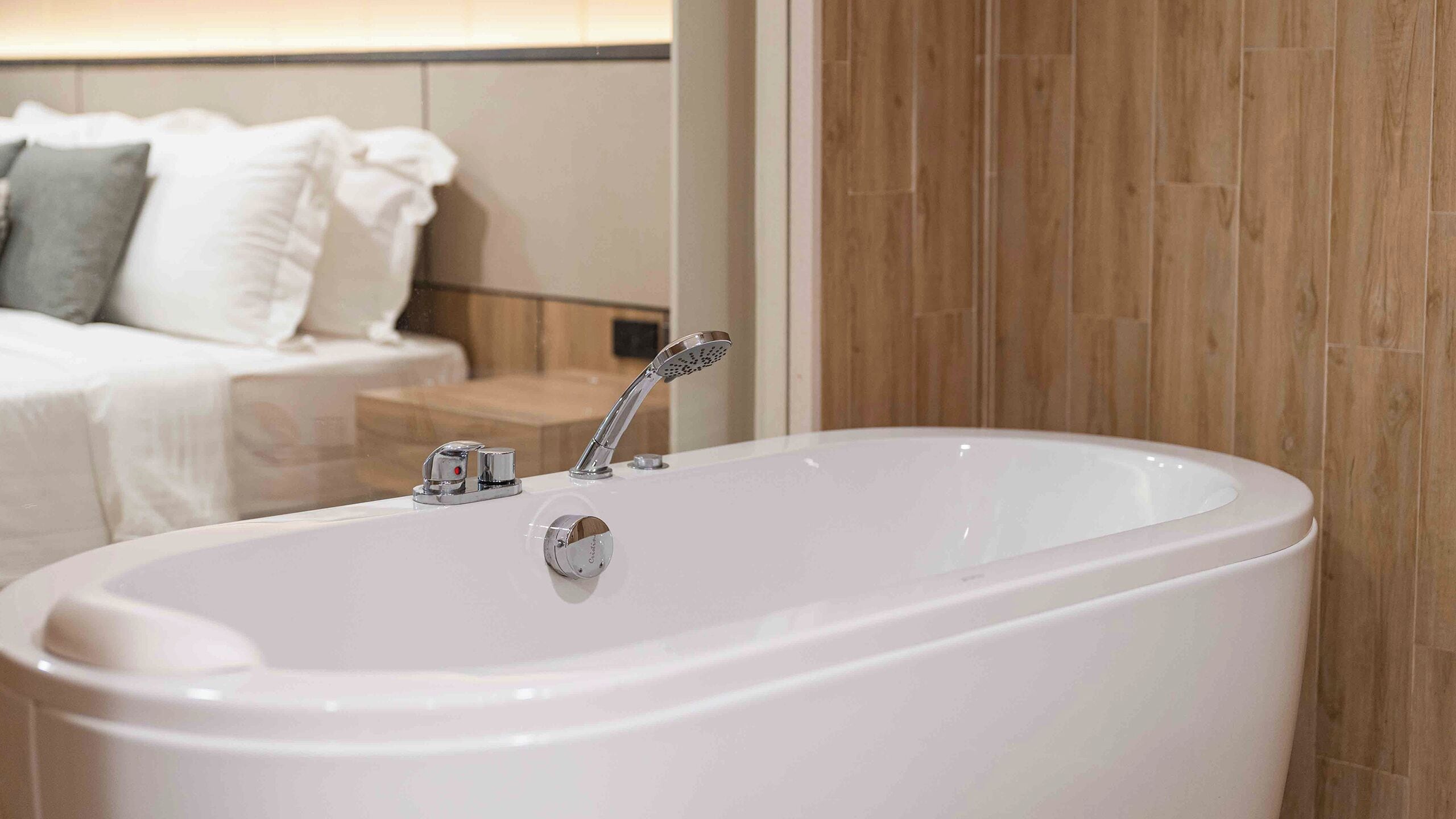 A modern bathroom with a freestanding bathtub, a handheld showerhead, and a vanity with a mirror.