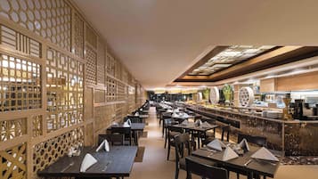 Un restaurante espacioso con una barra alargada, varias mesas y un separador decorativo de madera.