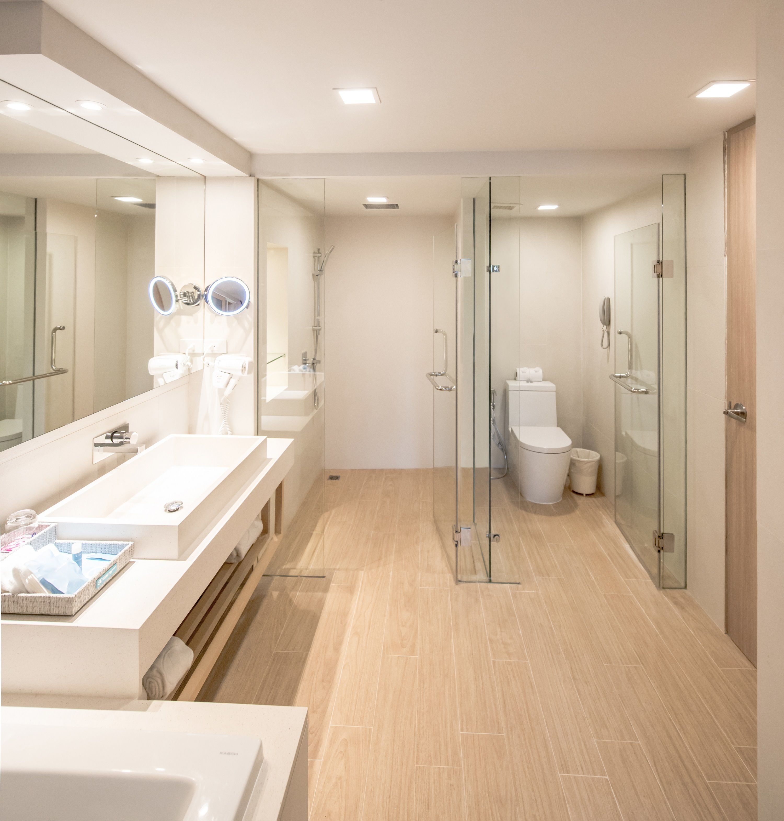 Un baño moderno con ducha envuelta en vidrio, un espejo grande y un tocador con lavabo y perchero.