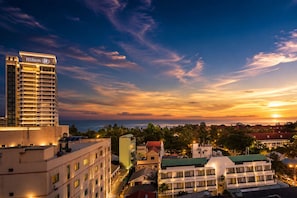 A high-rise hotel with a prominent sign, surrounded by other buildings and a sunset view. - City Beach Resort (Hua Hin)
