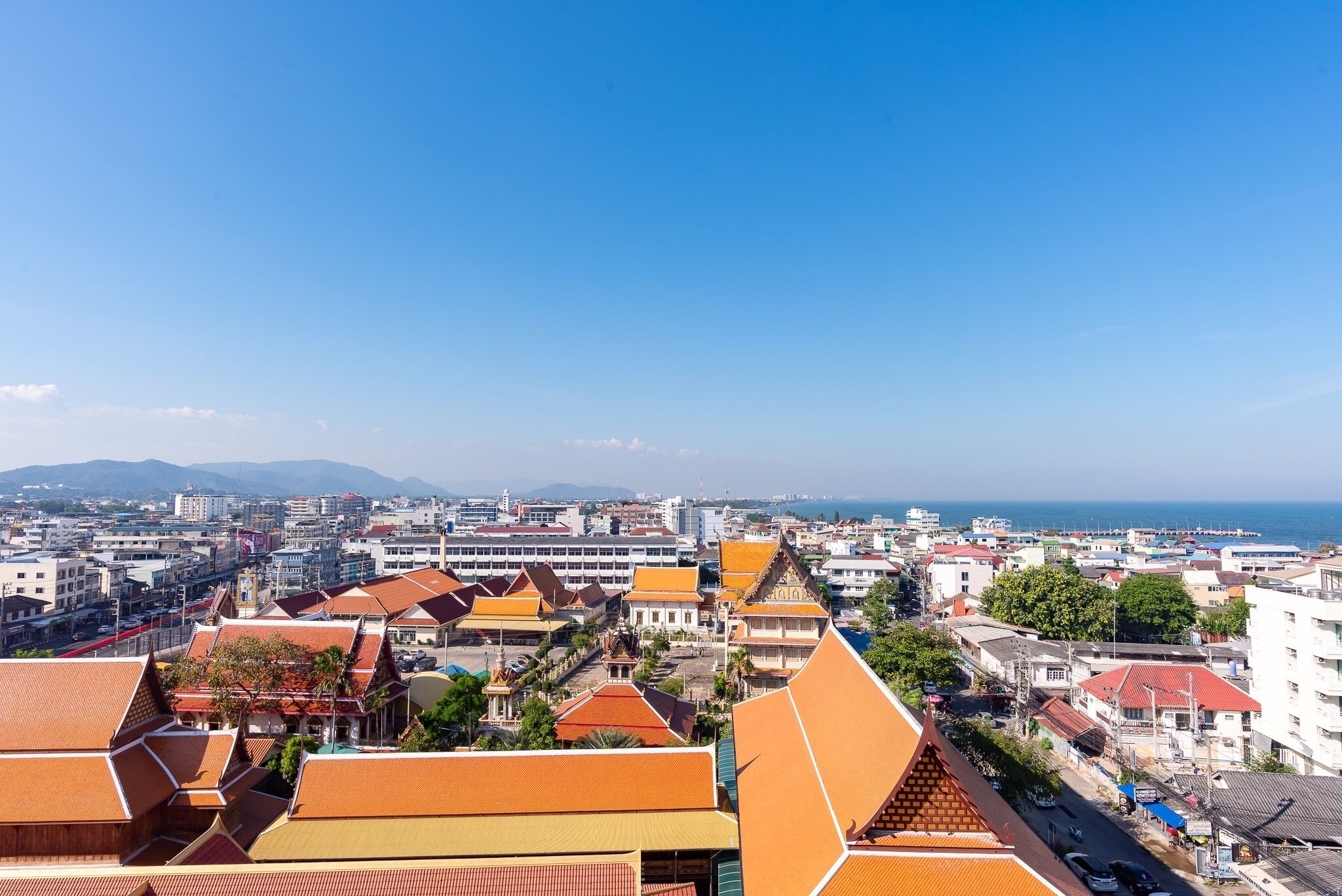 A cityscape with a mix of modern and traditional architecture, including buildings with orange roofs and a prominent white structure in the center.