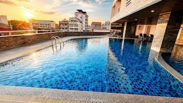 An indoor swimming pool with a tiled floor and a stone wall surrounding it.