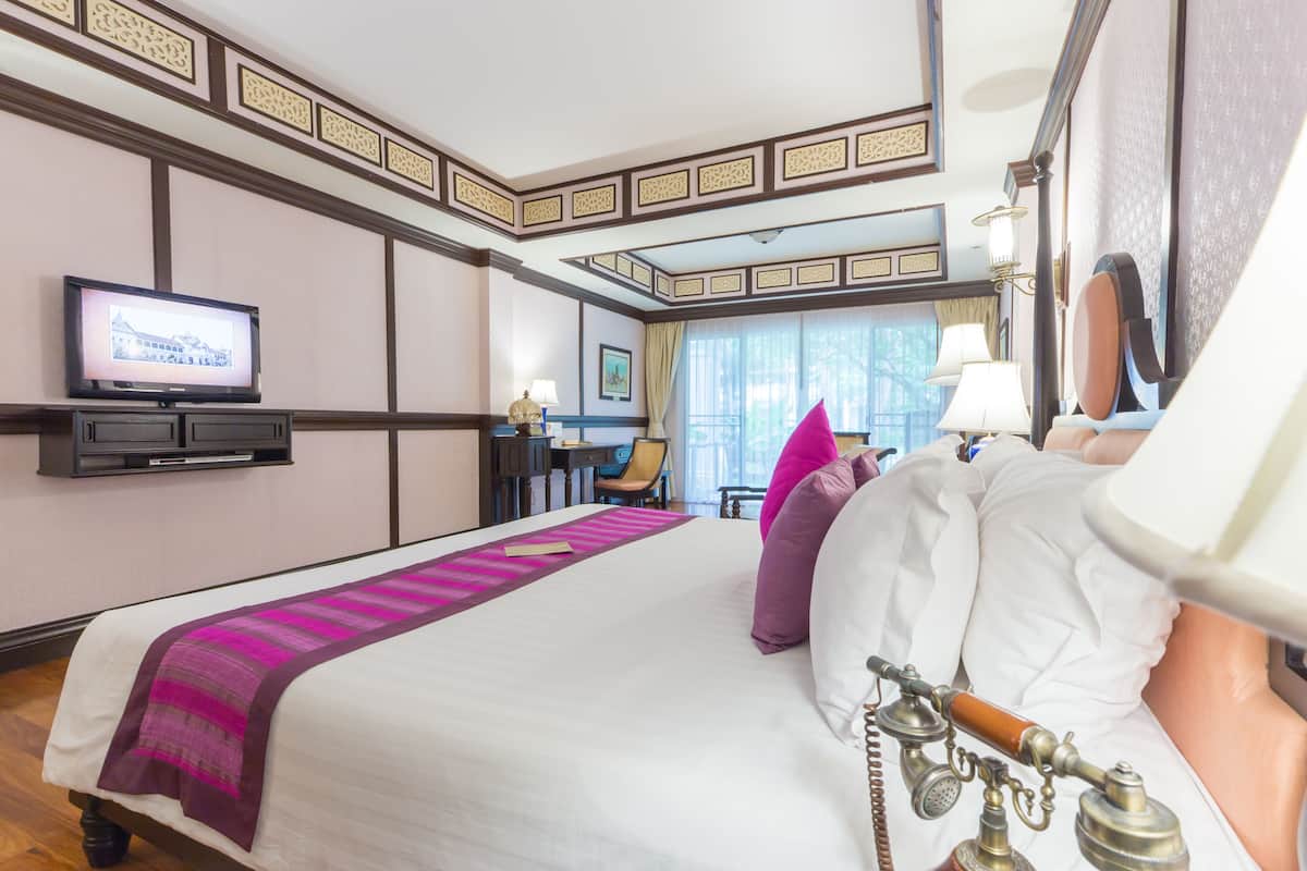A hotel room with a bed, a television, a desk, and a lamp.