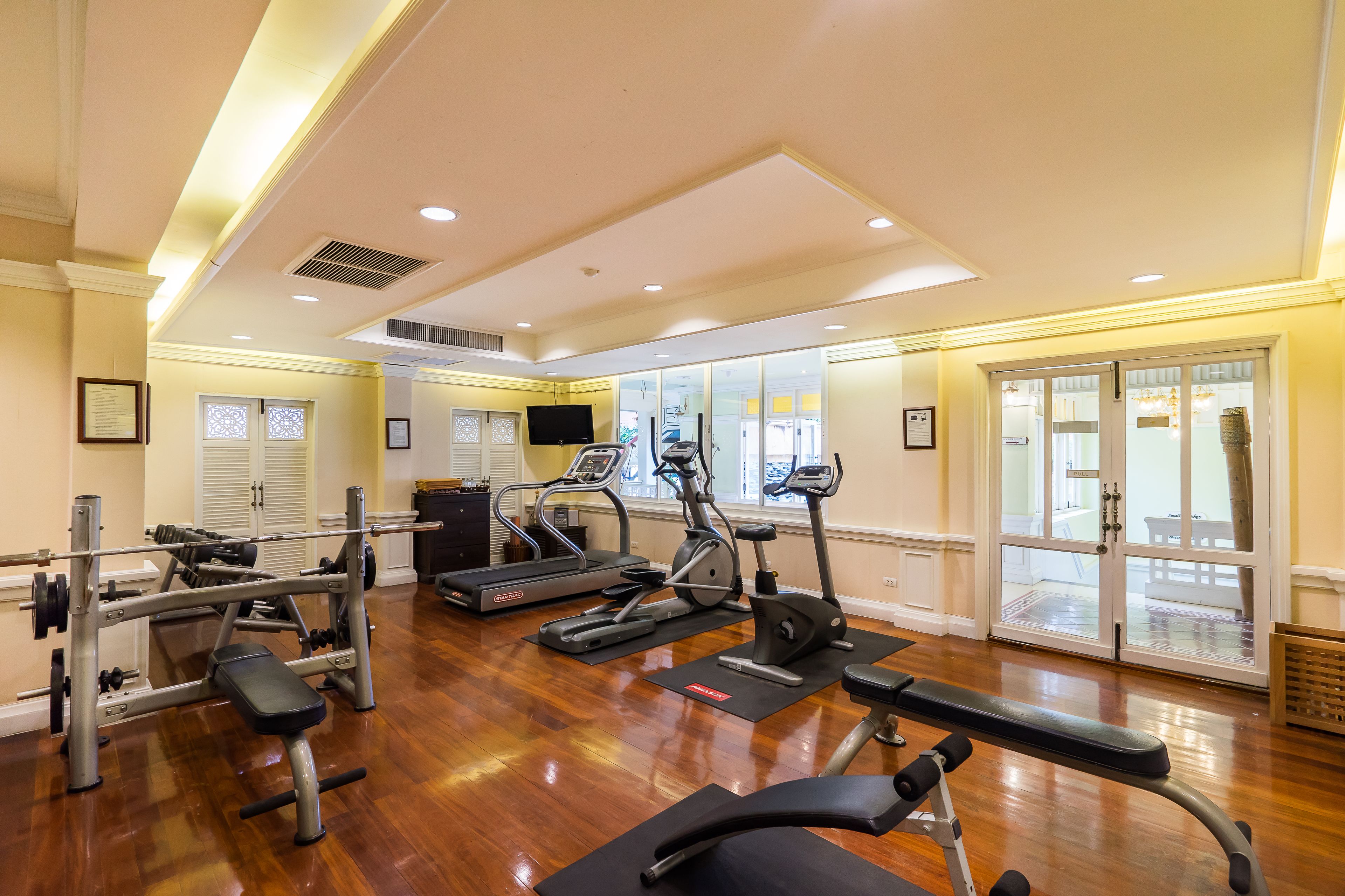 Un gimnasio con equipo de ejercicio, una banca y un televisor.