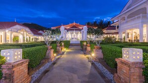 A well-lit pathway leading to a traditional building with a red roof, surrounded by neatly trimmed hedges and brick walls. - Wora Bura Hua Hin Resort and Spa (Hua Hin)