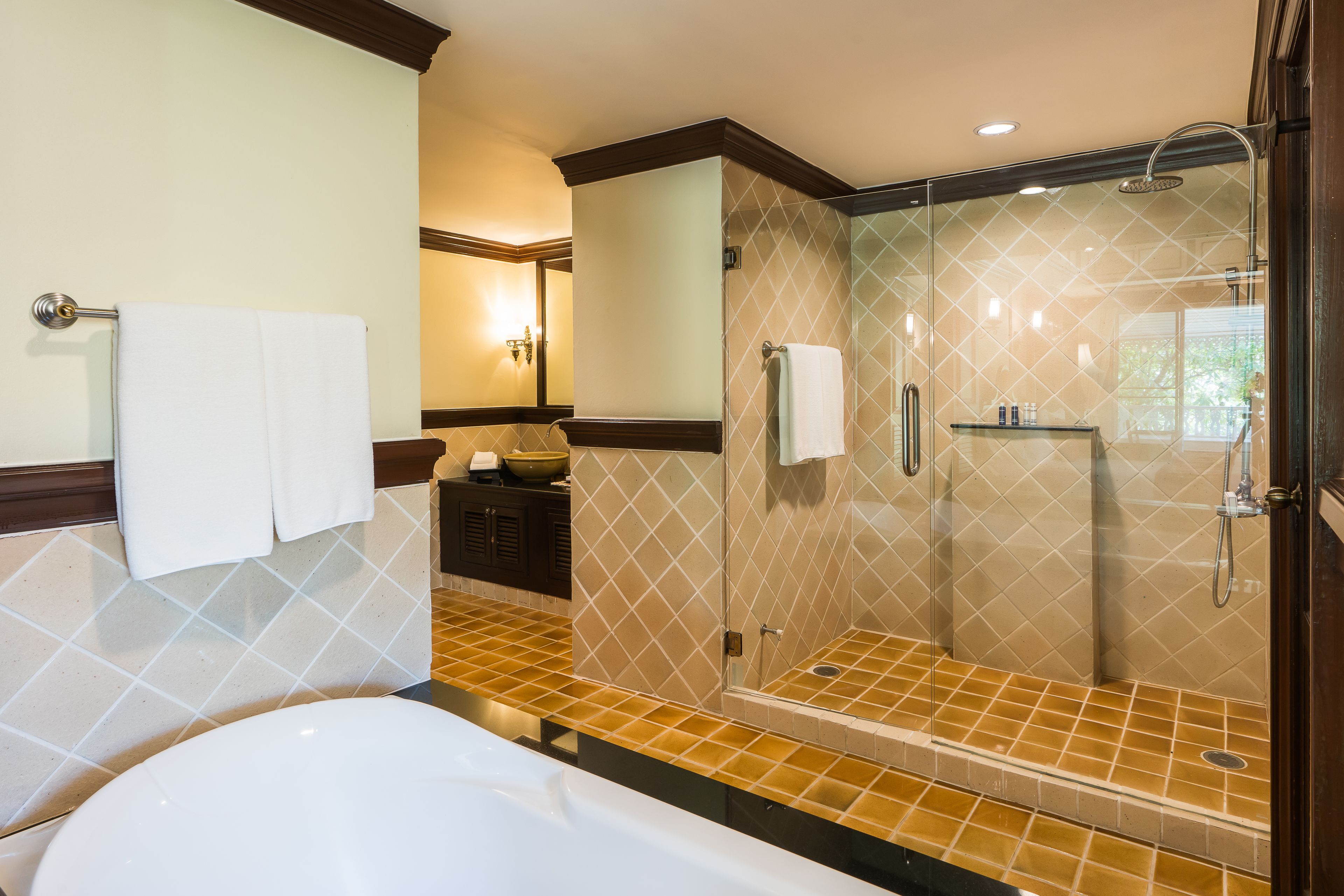 A modern bathroom with a glass-enclosed shower, a bathtub, and a vanity with a mirror and towel rack.