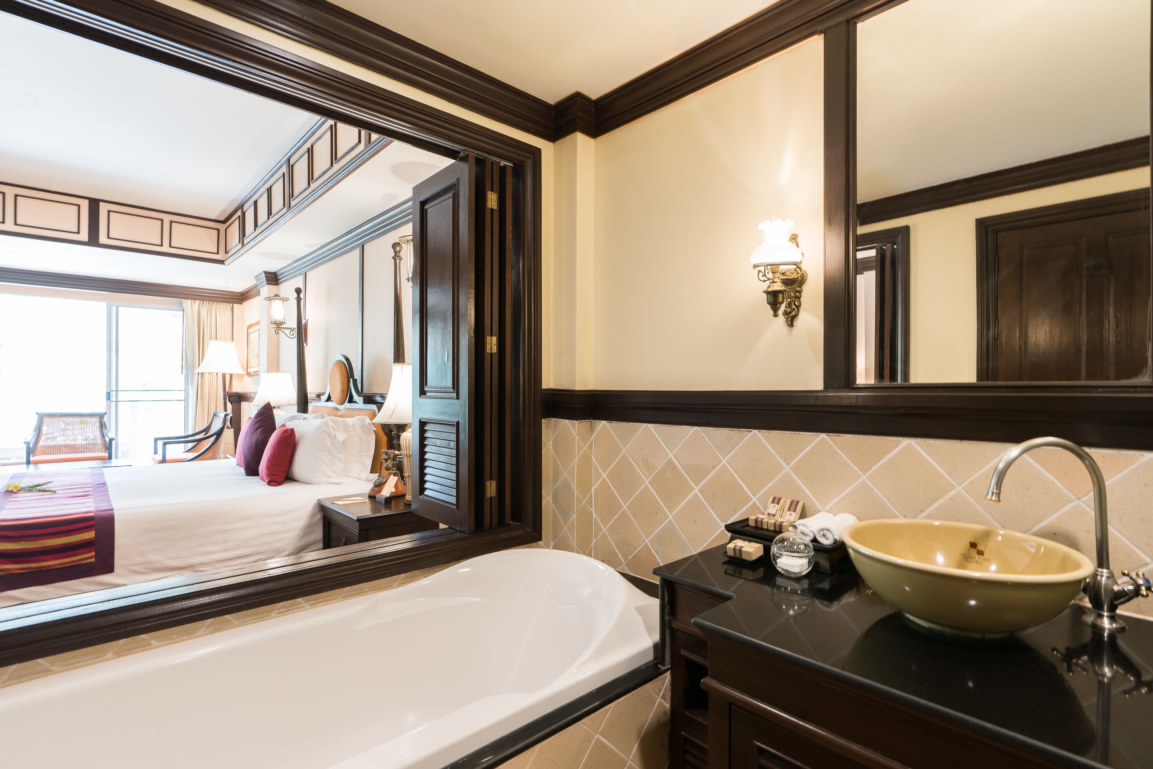 A hotel room with a large bed, a bathroom with a bathtub, a sink, and a mirror.