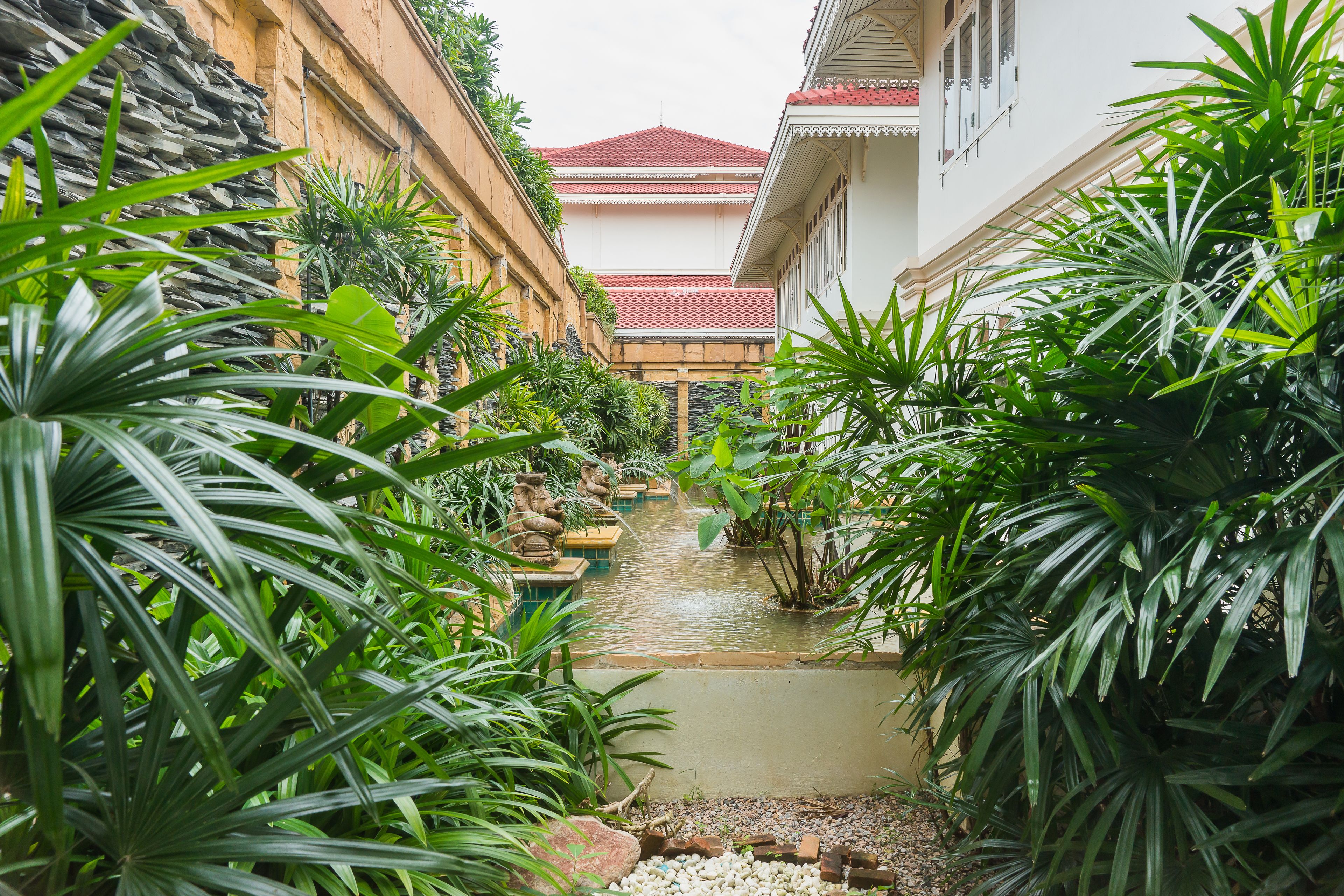 En smal kanal omgivet af frodig vegetation og traditionel arkitektur.