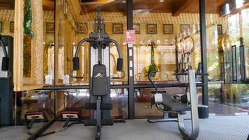 Un gimnasio con equipo de ejercicio, incluyendo una máquina de prensa de piernas y una bicicleta estática.