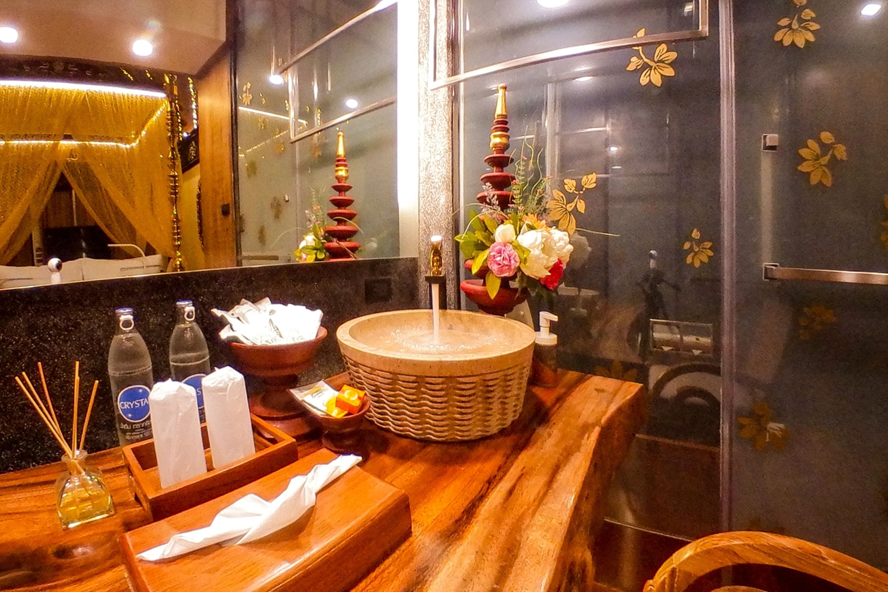 A bathroom with a wooden vanity, a large mirror, a sink with a decorative vase, and a window with floral decals.