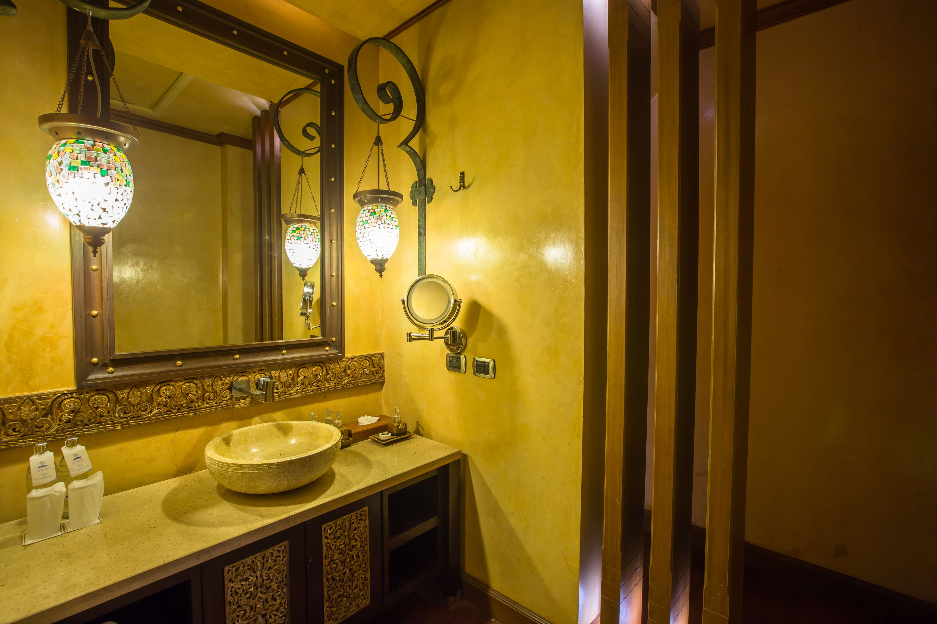 A bathroom with a round sink, a mirror, and two wall-mounted lights.