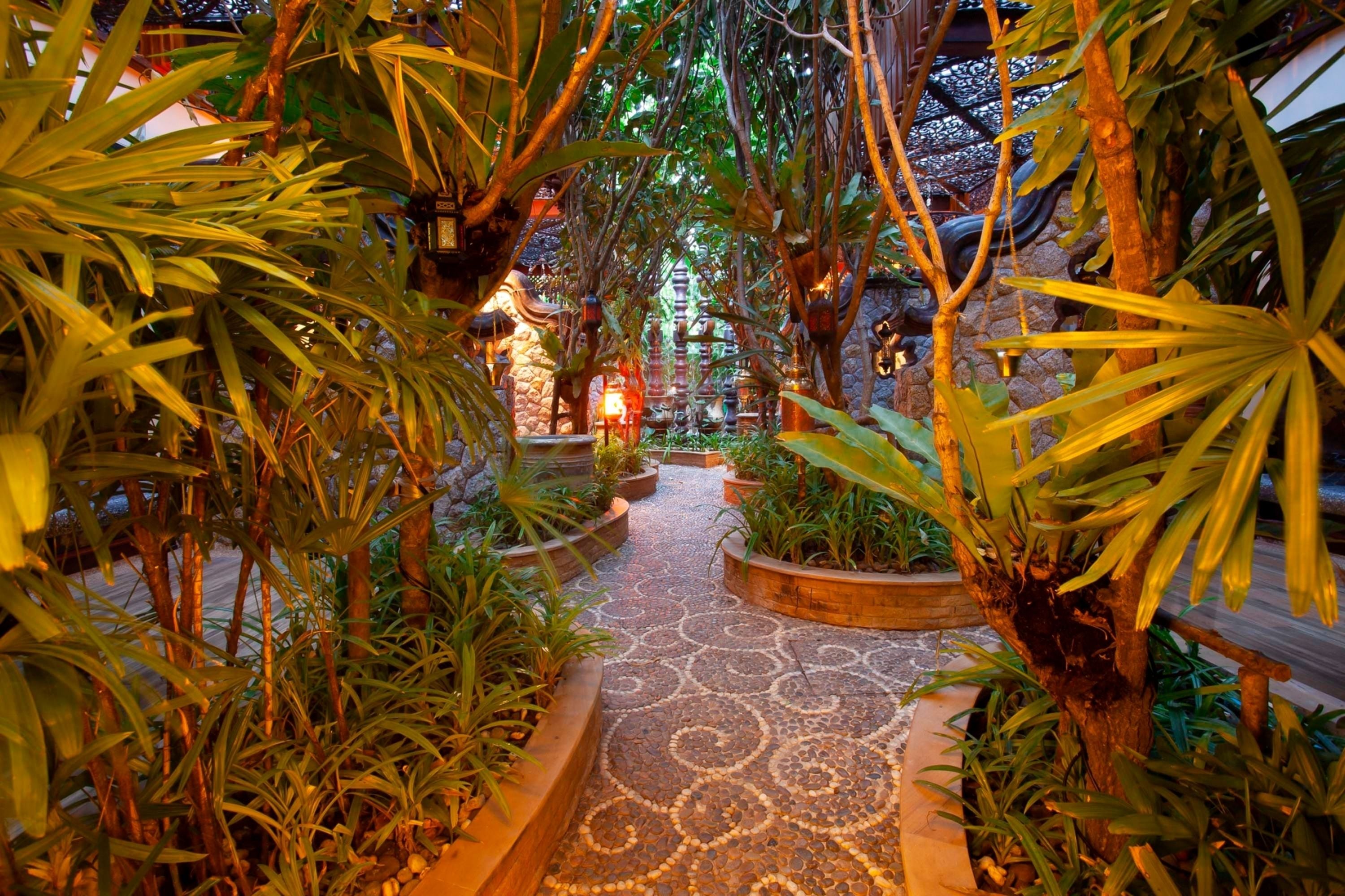 An indoor garden pathway with tropical plants and a patterned floor.