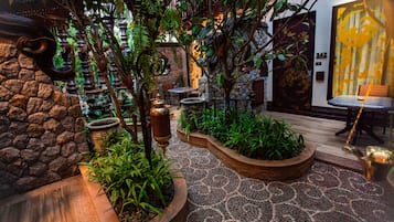 An indoor garden with stone walls, a mosaic floor, and various plants.