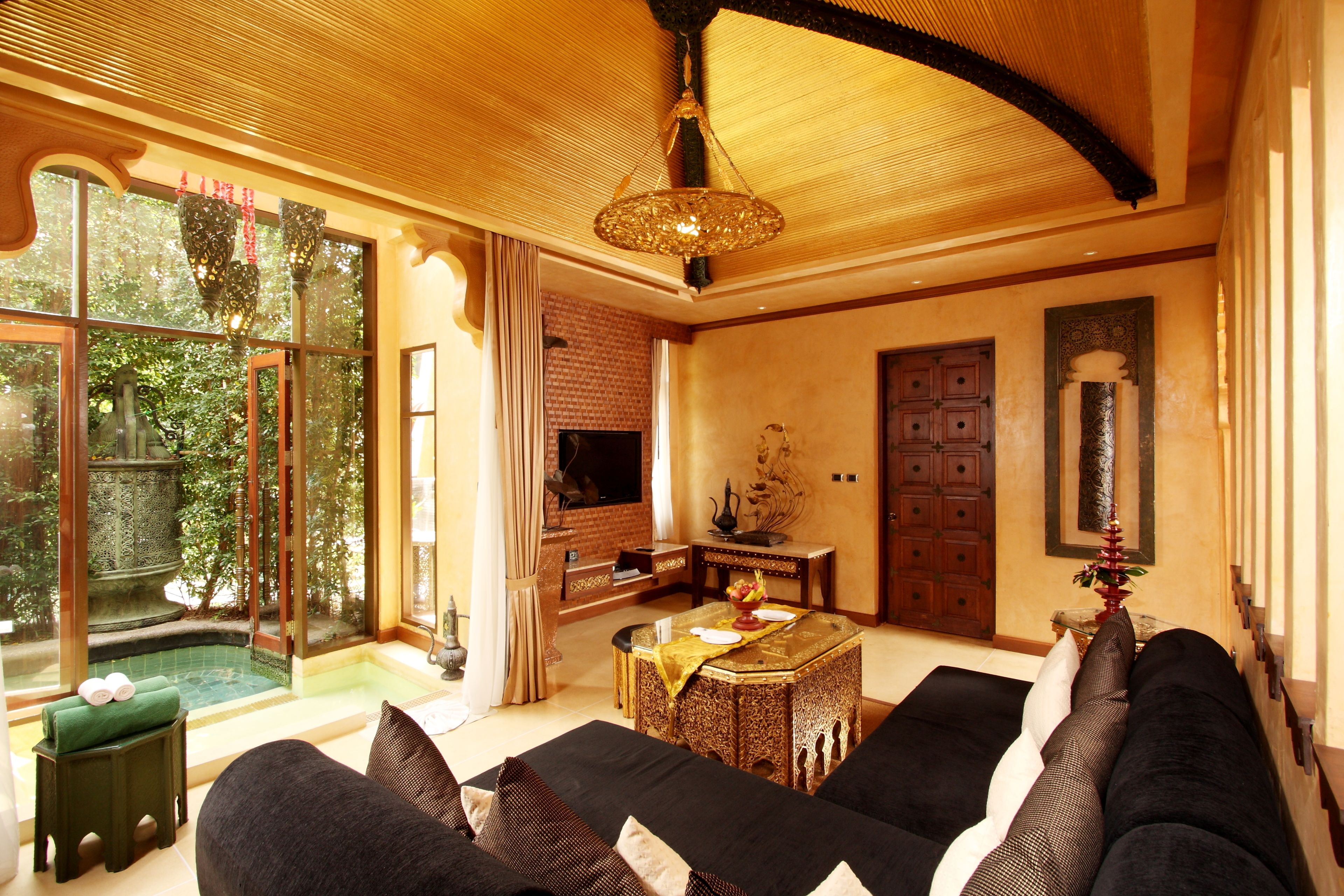 A spacious living area with a large sofa, a small table, and a view of a pool and greenery outside.