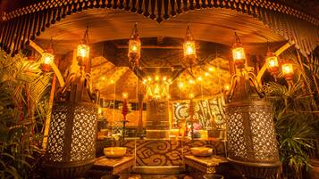 Un intérieur traditionnel agrémenté de lanternes décoratives, de motifs ornementaux sur les murs et d’un espace salon central.