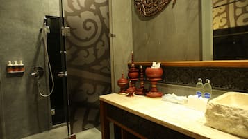 Un baño con ducha, tocador con espejo y adornos.