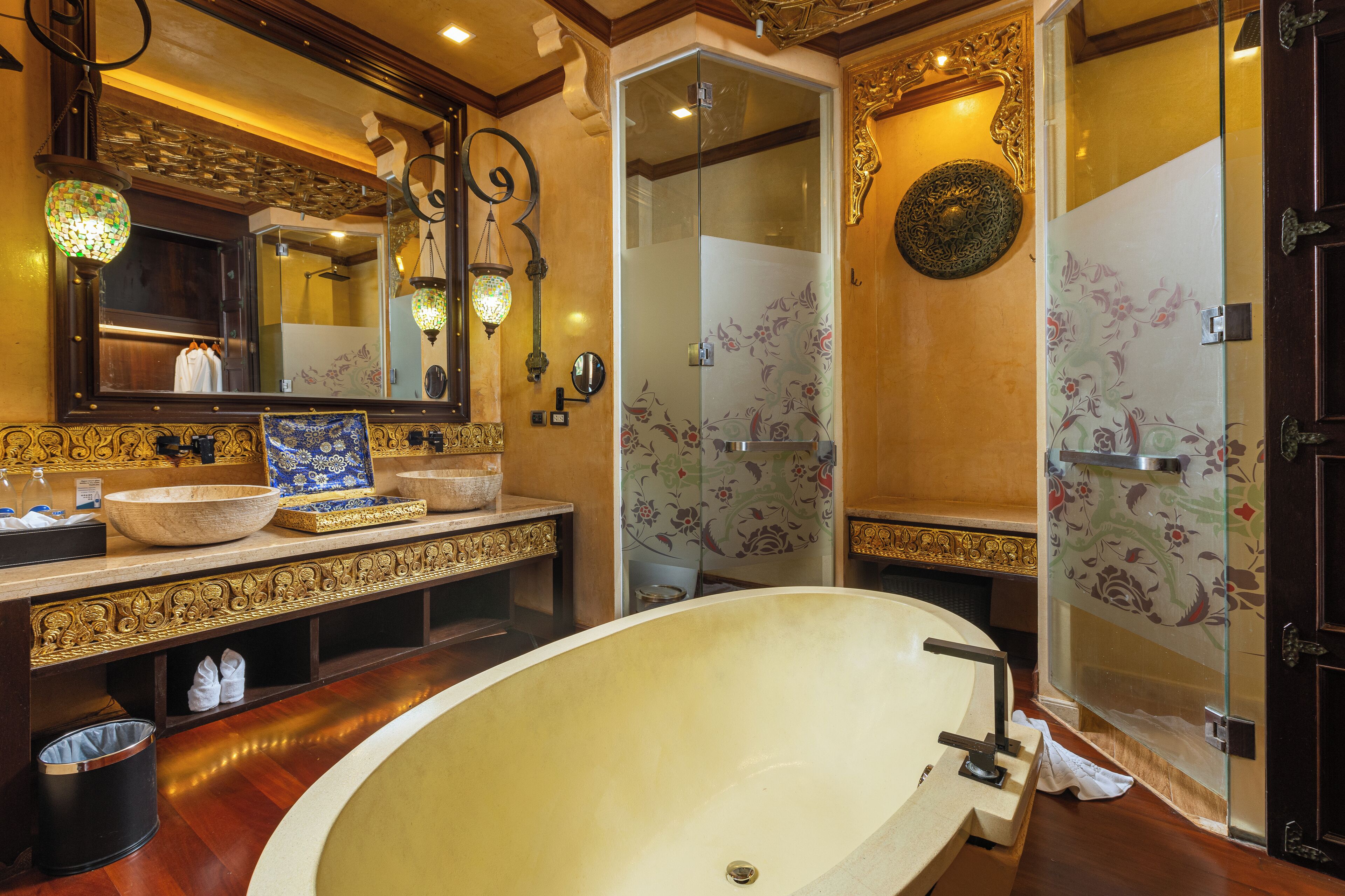 Une salle de bain dotée d’une grande baignoire, d’un lavabo aux détails raffinés et d’un miroir encadré.