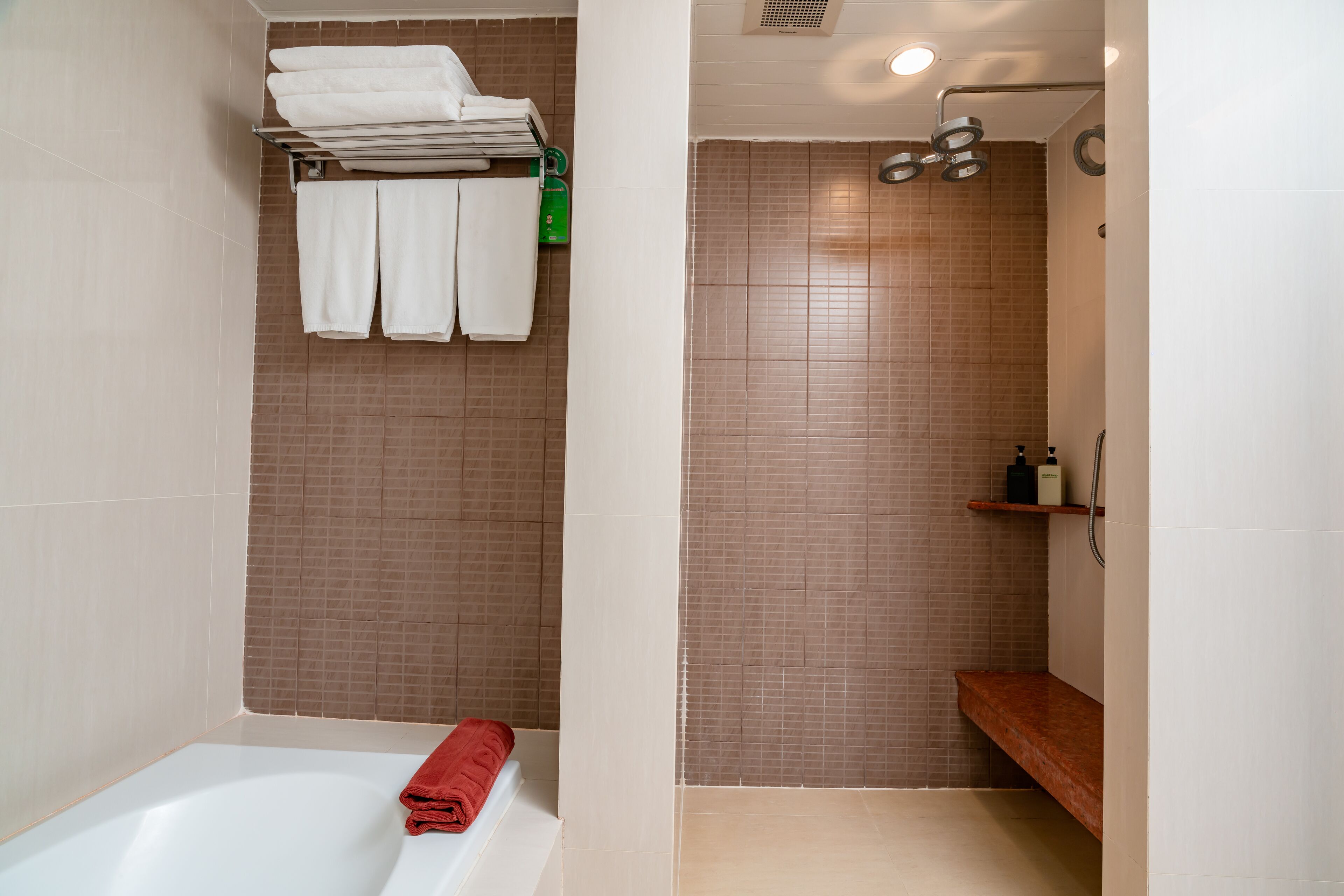 A modern bathroom with a bathtub, a shower area, and a towel rack with folded towels.