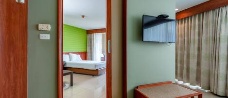 A hotel room with a bed, a television mounted on the wall, and a small wooden bench.