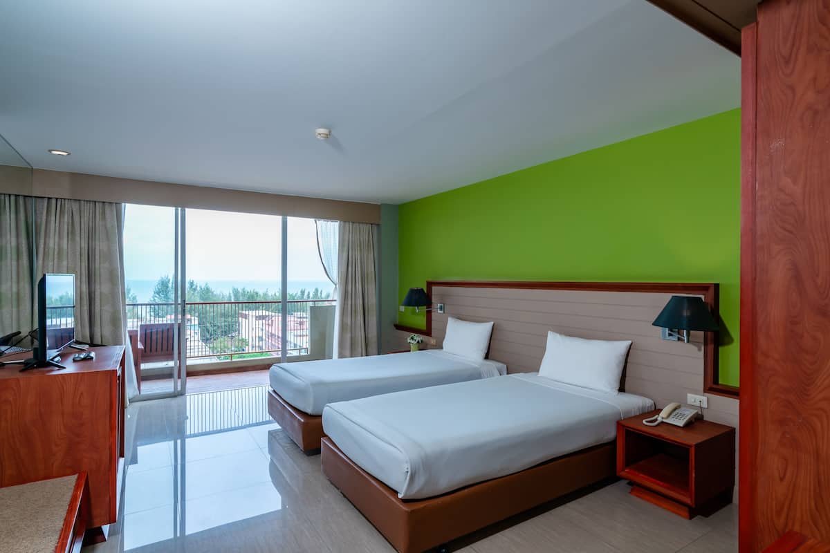 A hotel room with two beds, a desk with a computer, a phone, and a view of the city.