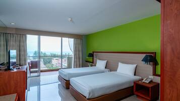 A hotel room with two beds, a desk with a computer, a phone, and a view of the city.
