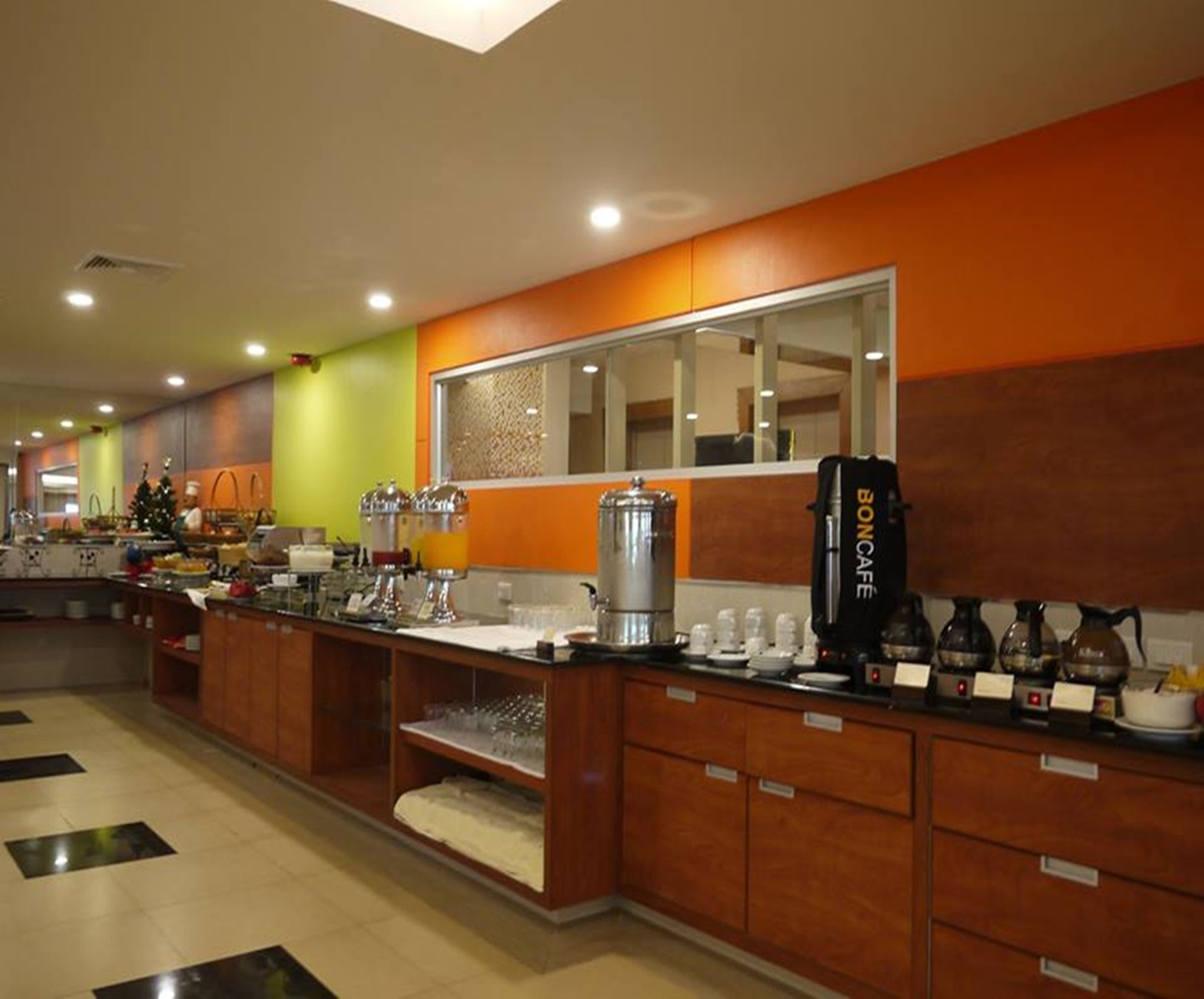 A hotel kitchen with a buffet setup, including a coffee machine and various food stations.
